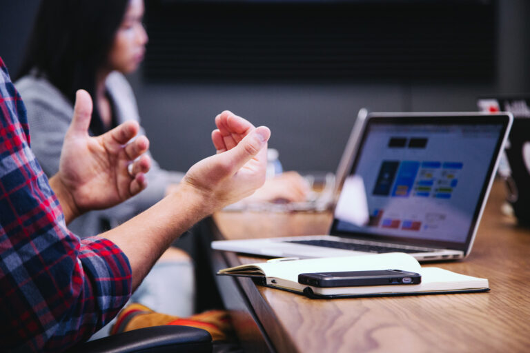 A picture of a guy's hands with a computer in the background