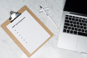A photo of a clipboard and a Macbook depicting successful app development