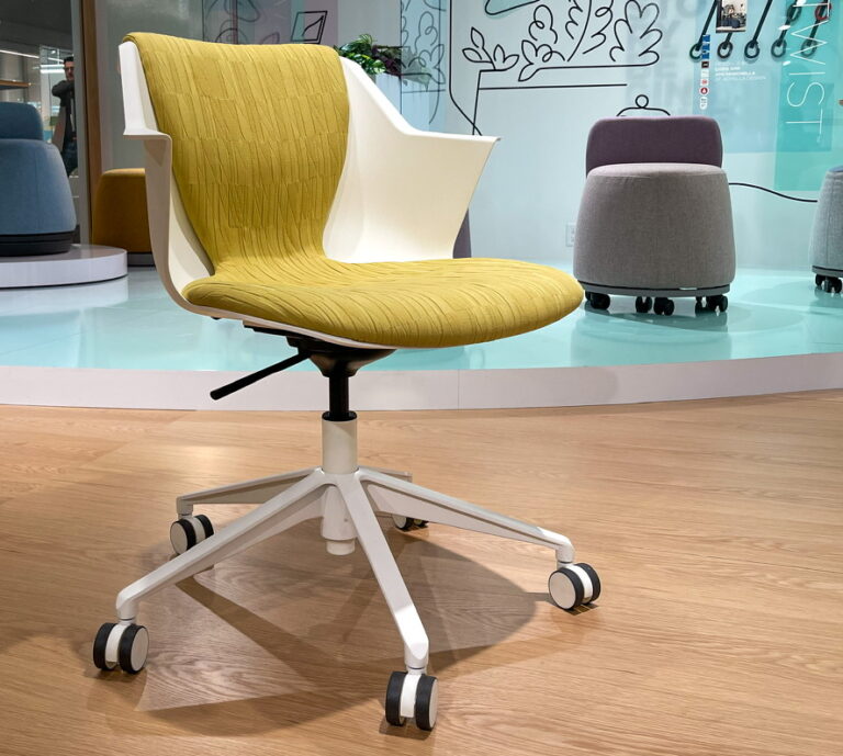 A lime green and white chair with wheels from the Om Seating display at NeoCon 2023